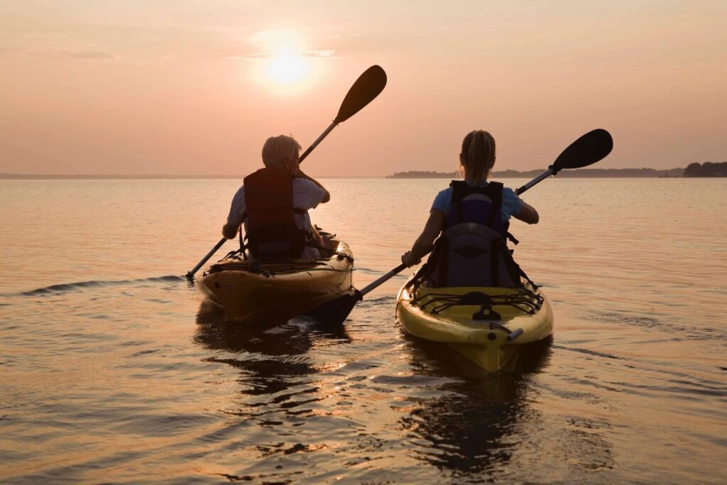 Two people paddling on the river at sunset